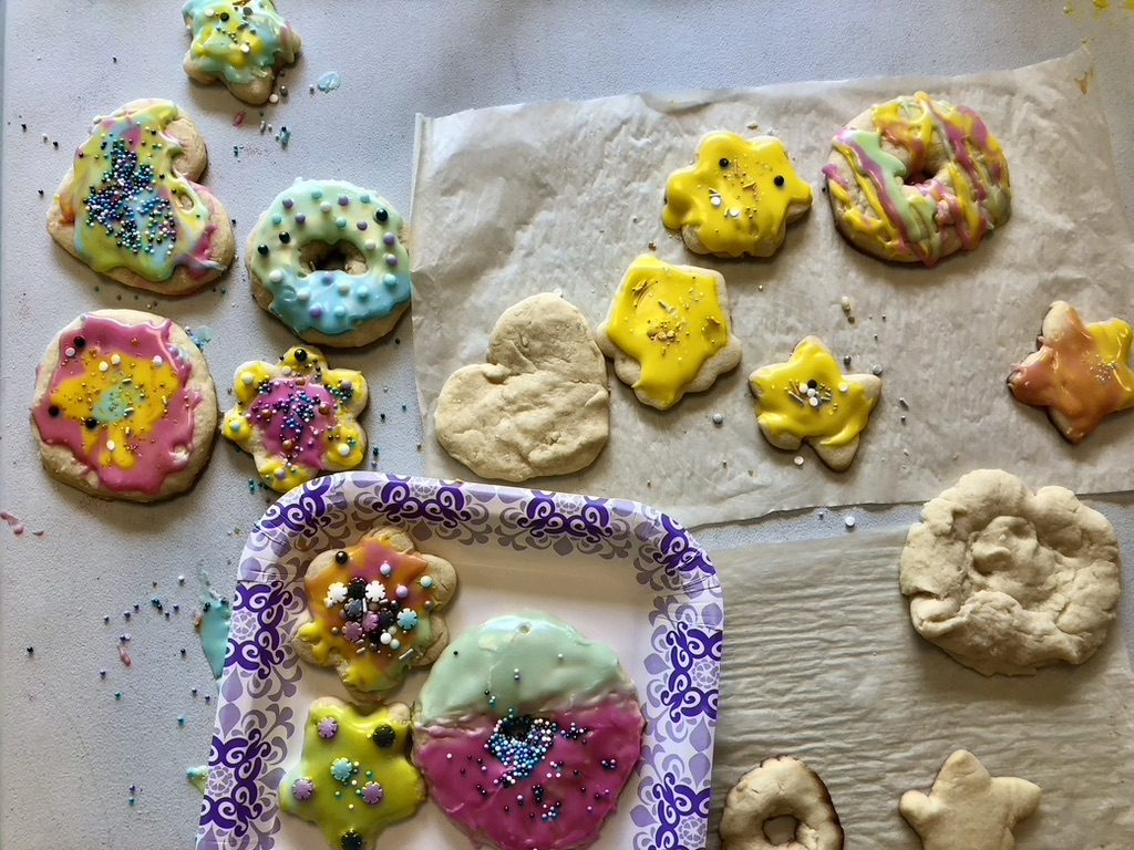 Iced and sprinkled sugar cookies laid out on parchment