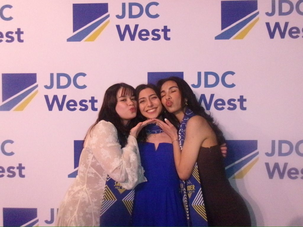 Three students in formal wear at the JDC West backdrop