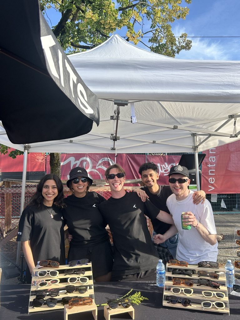 The KITS team at an outdoor pop-up booth with sunglasses on display